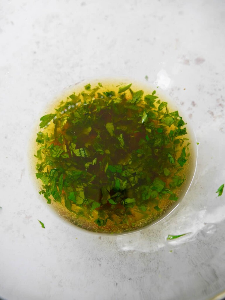 A small bowl of olive oil mixed with garlic, red chilli and fresh herbs.