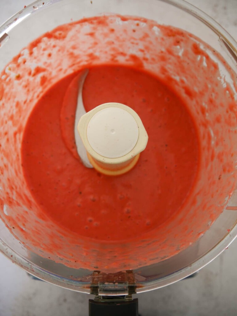 A food processor bowl filled with blitzed raspberry vinaigrette dressing.