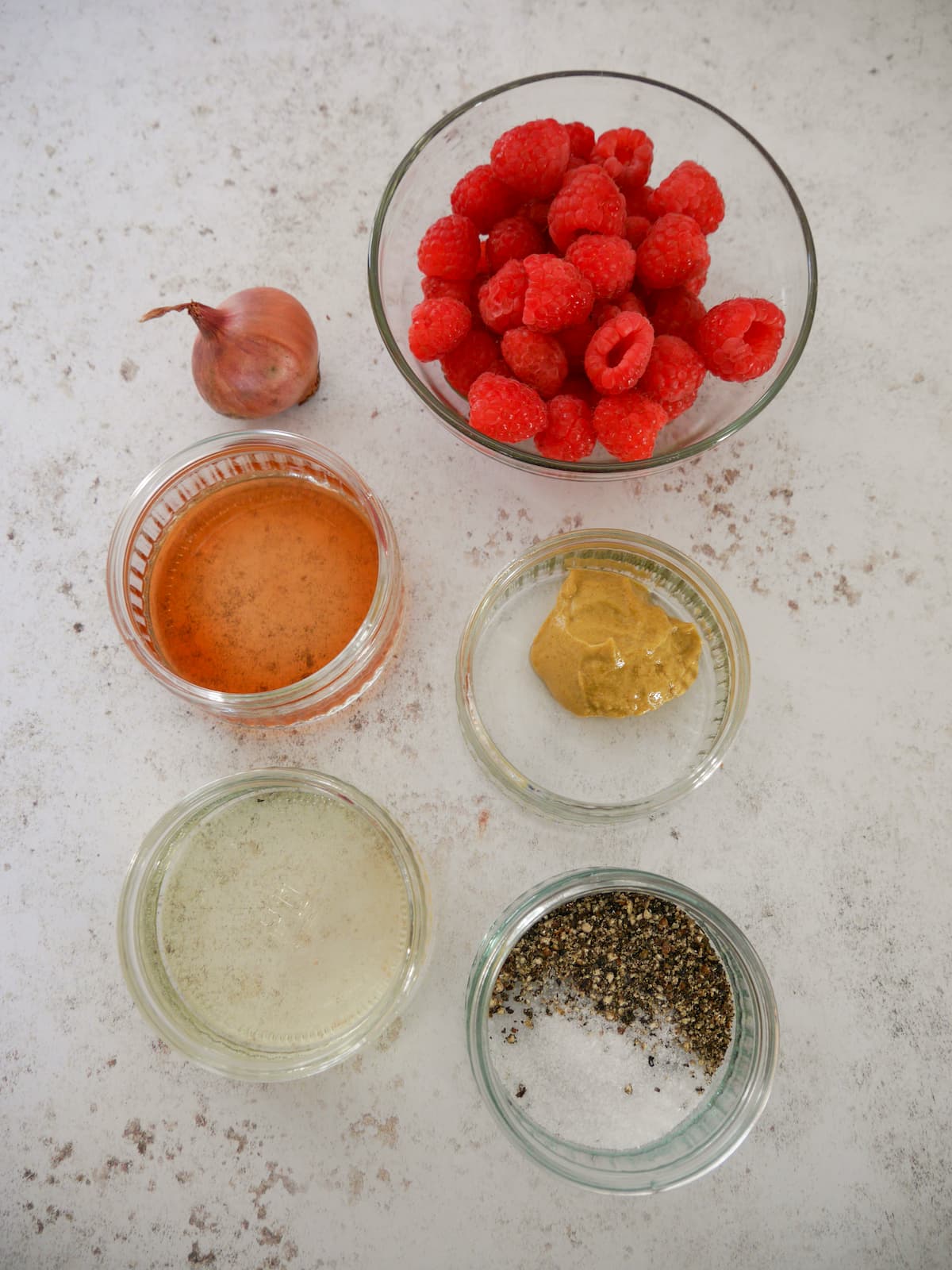 Individual recipe ingredients for making a fresh raspberry vinaigrette dressing.