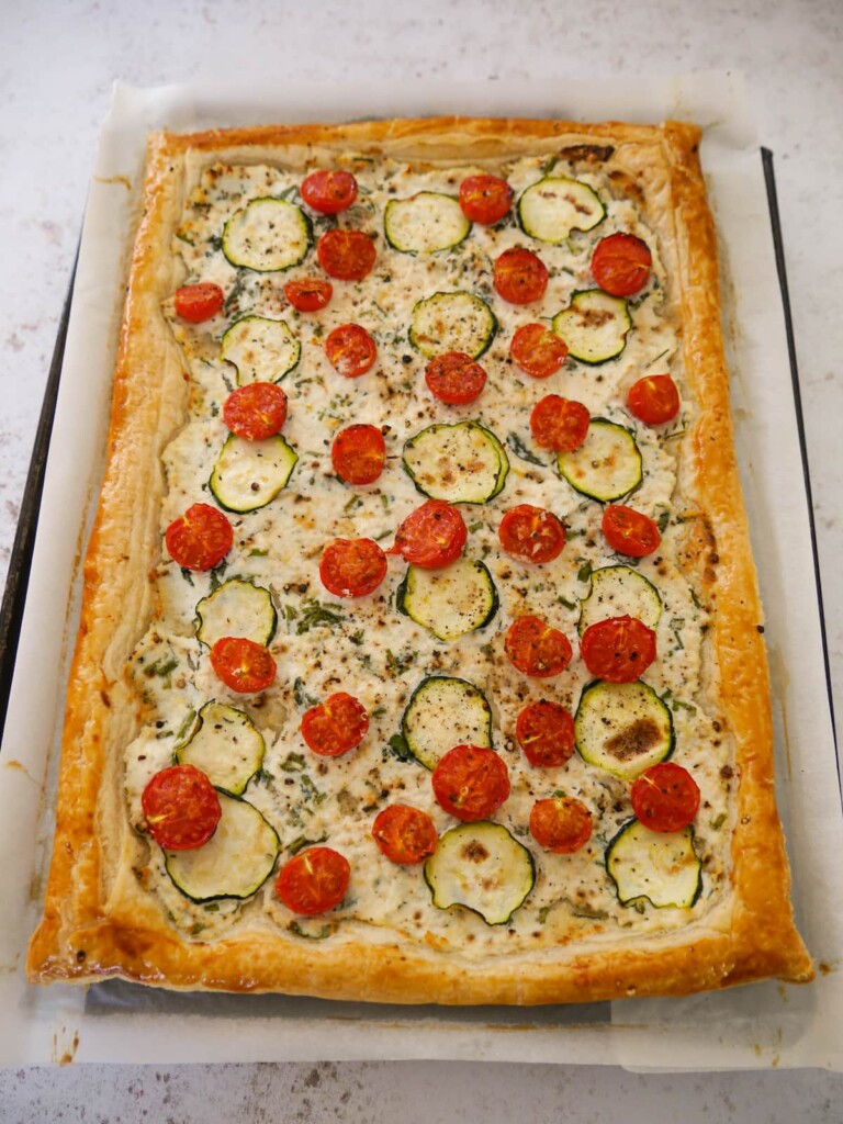 A baking sheet topped with a freshly baked tomato and courgette puff pastry tart.