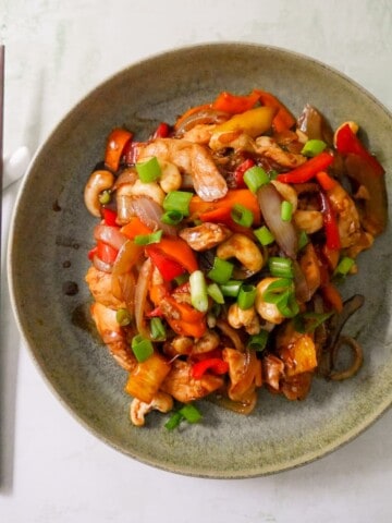 A bowl of stir-fried chicken and cashew nuts, with chopsticks set alongside.