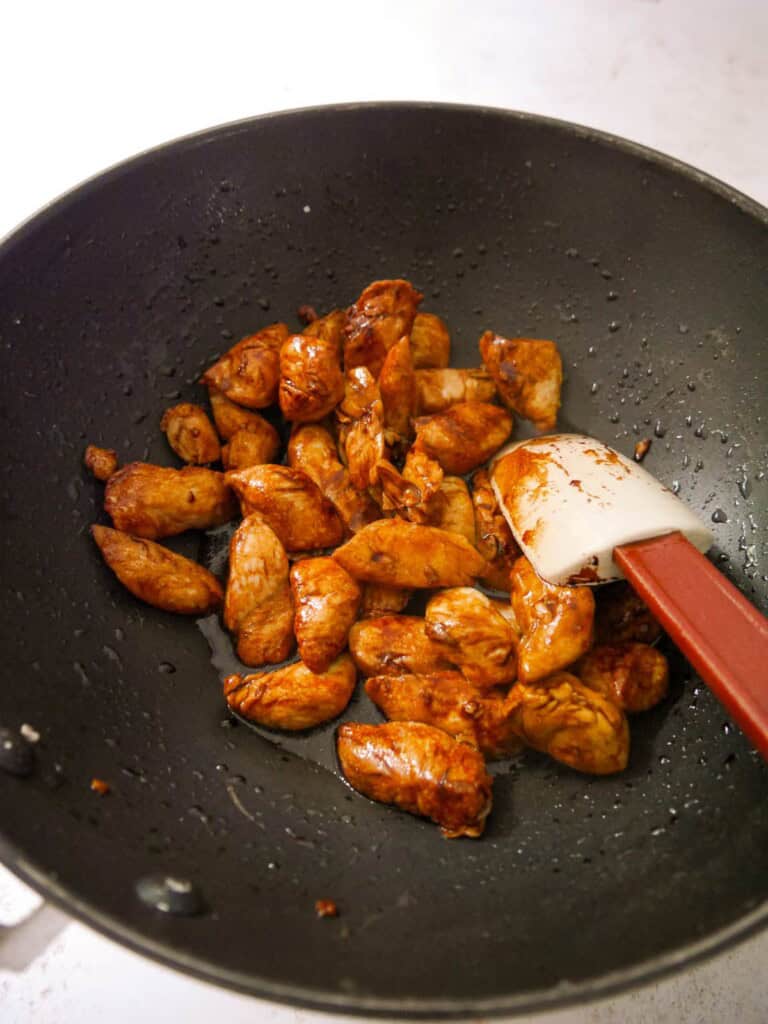 A wok of stir fried chicken with soy sauce and oyster sauce.