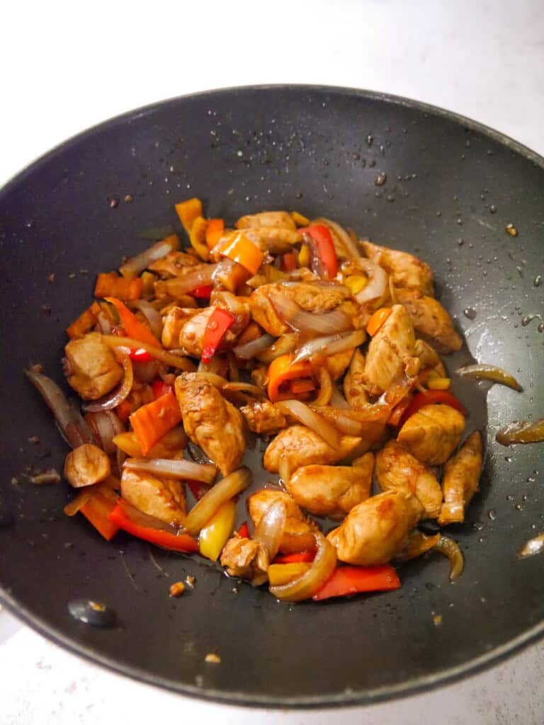 A wok of stir-fried chicken and vegetables.