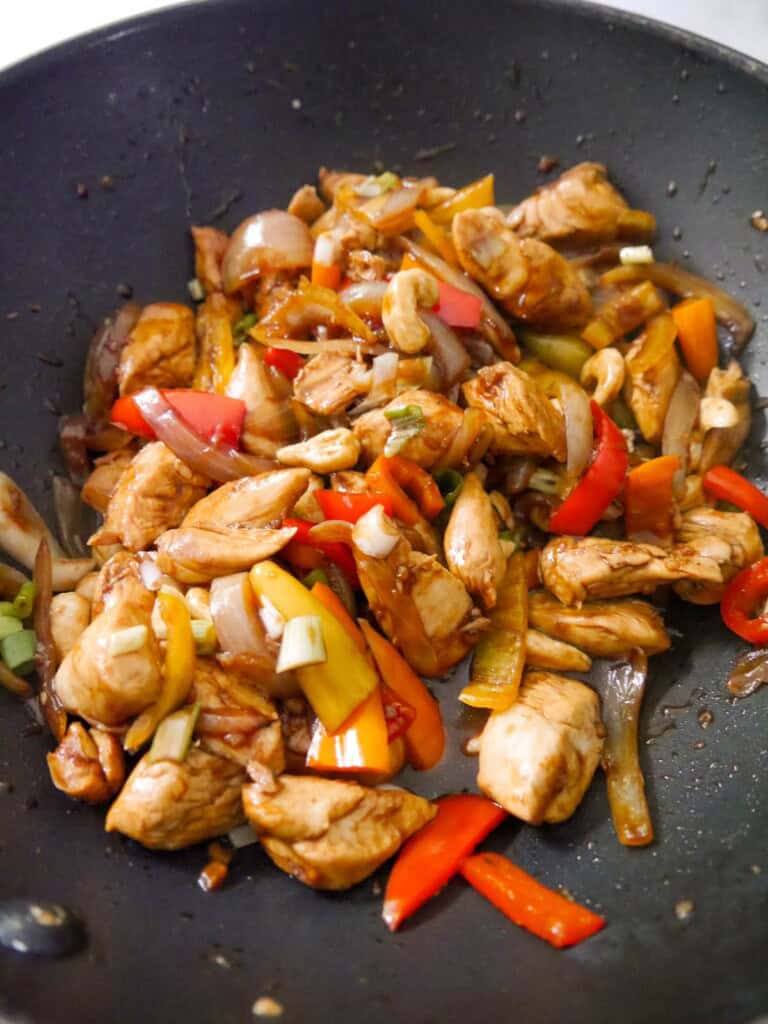 A wok of stir fried chicken and vegetables, with added soy, oyster sauce and cashew nuts.
