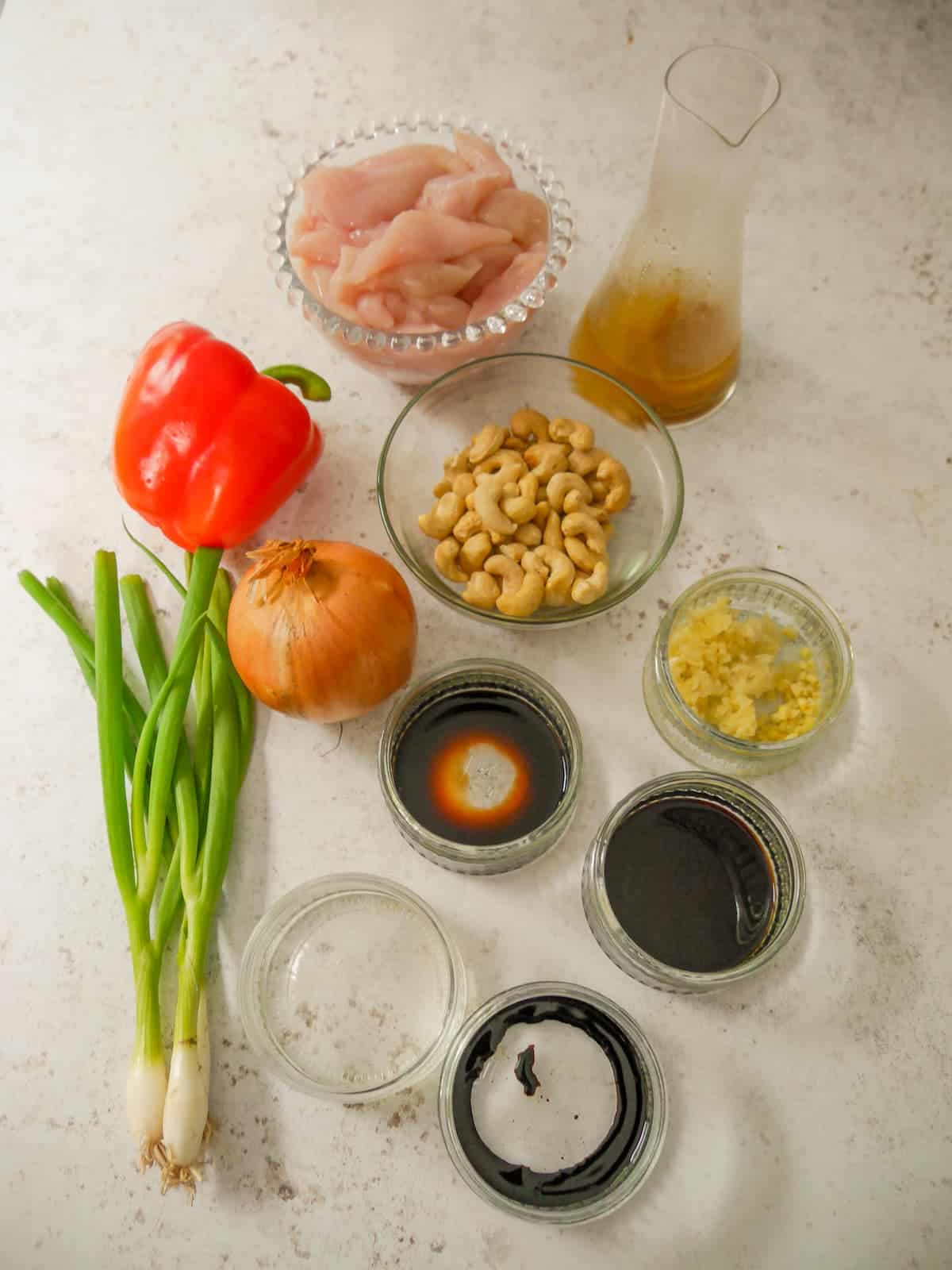 Individual recipe ingredients for making stir-fried chicken and cashews.