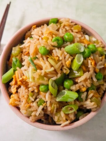 A bowl of egg fried rice, garnished with sliced spring onions.