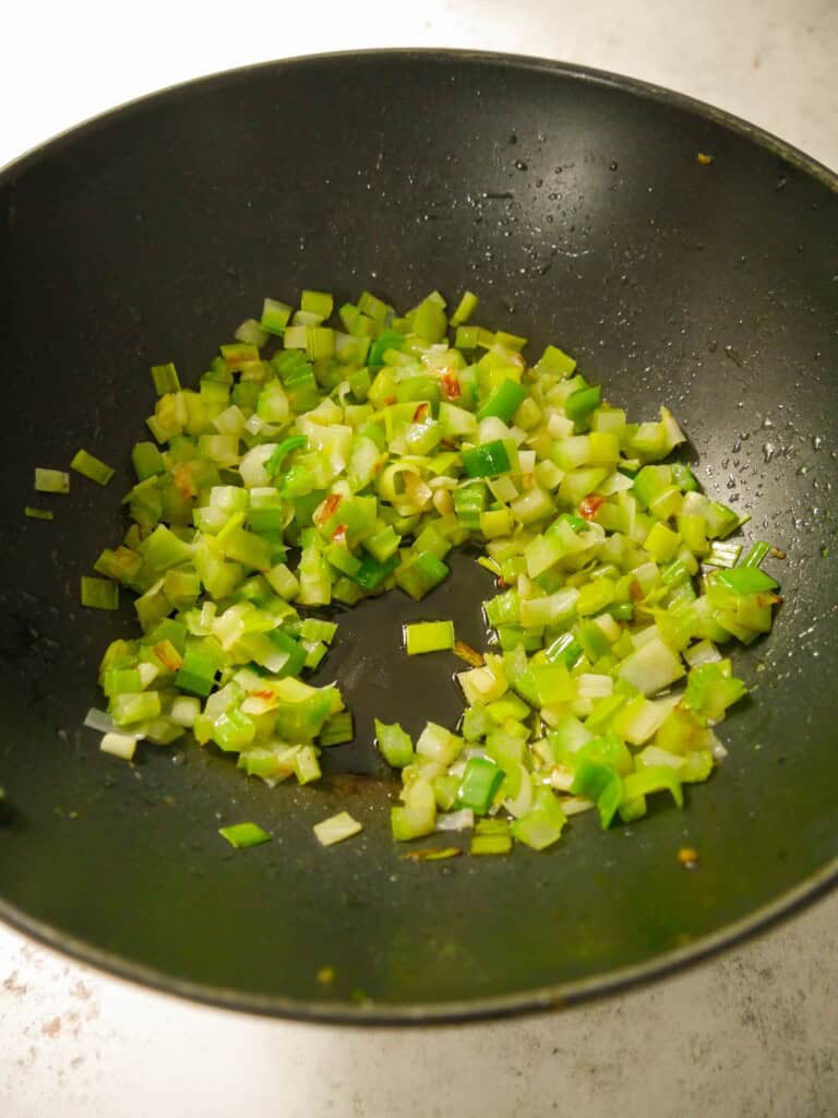 A wok of stir-fried diced celery and leek.