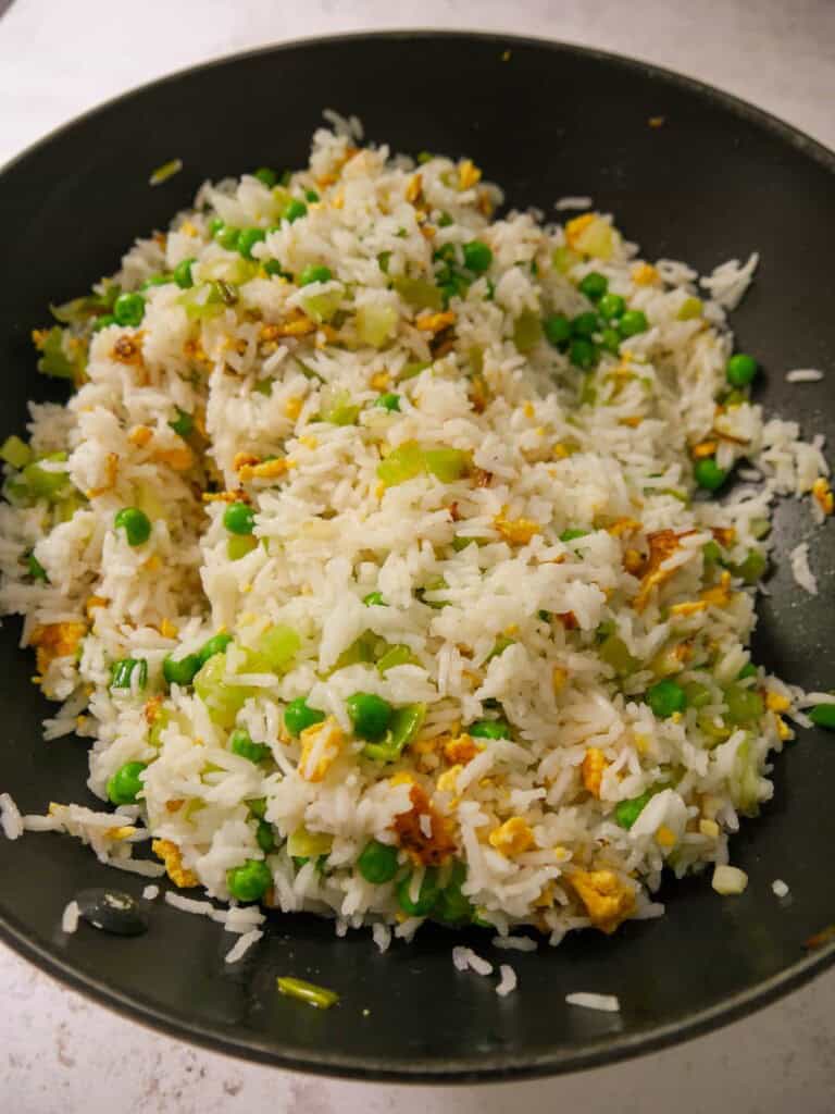 A wok of stir fried rice with egg, leek, celery and garden peas.