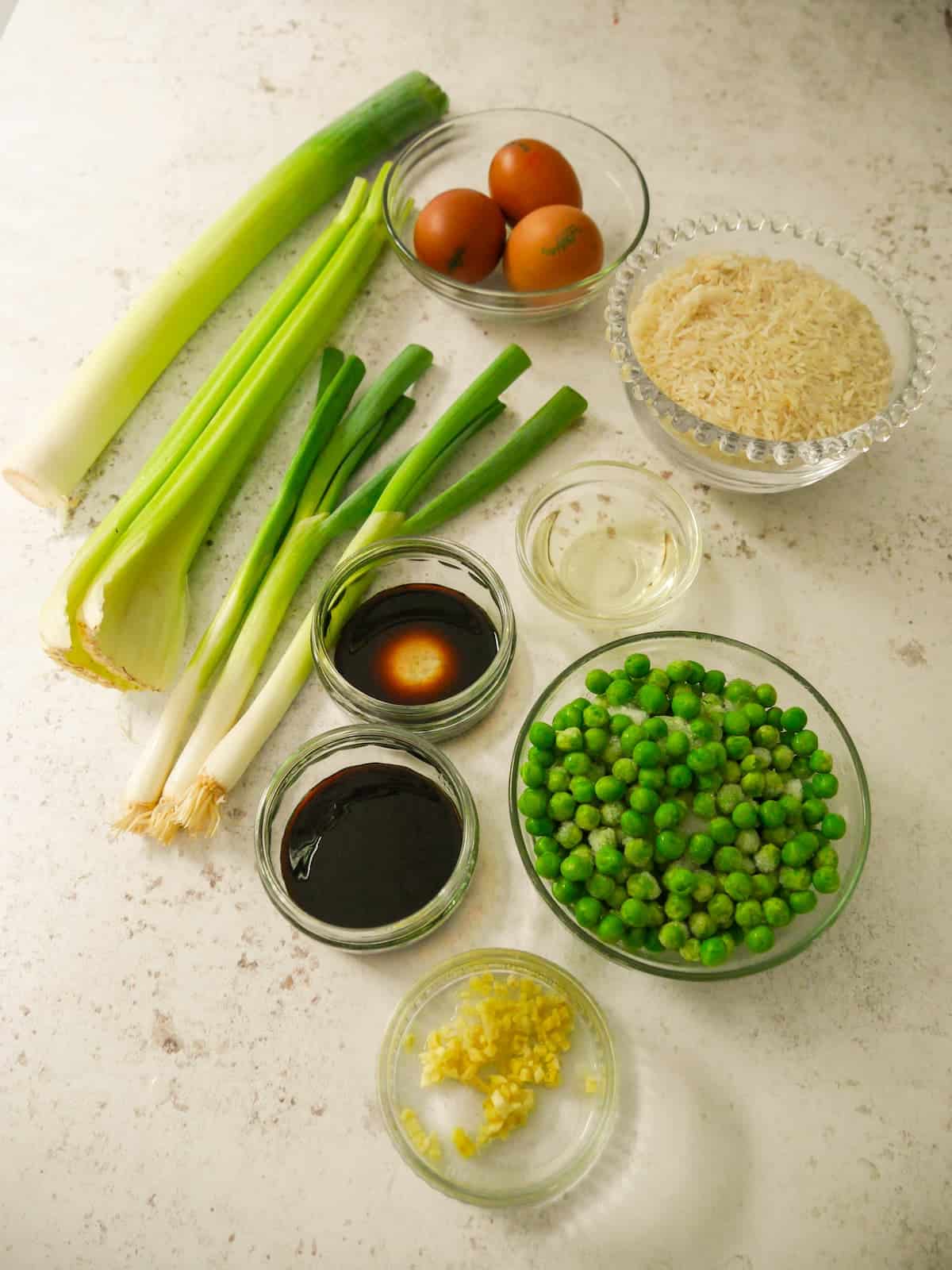 Individual recipe ingredients for making egg fried rice.