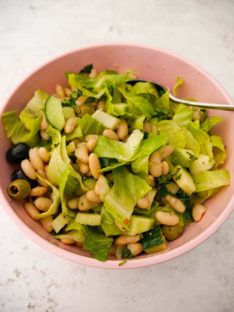 A large bowl filled with dressed white bean and feta salad.