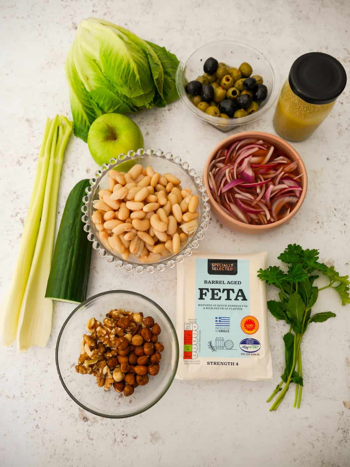 Individual recipe ingredients for making white bean and feta salad.