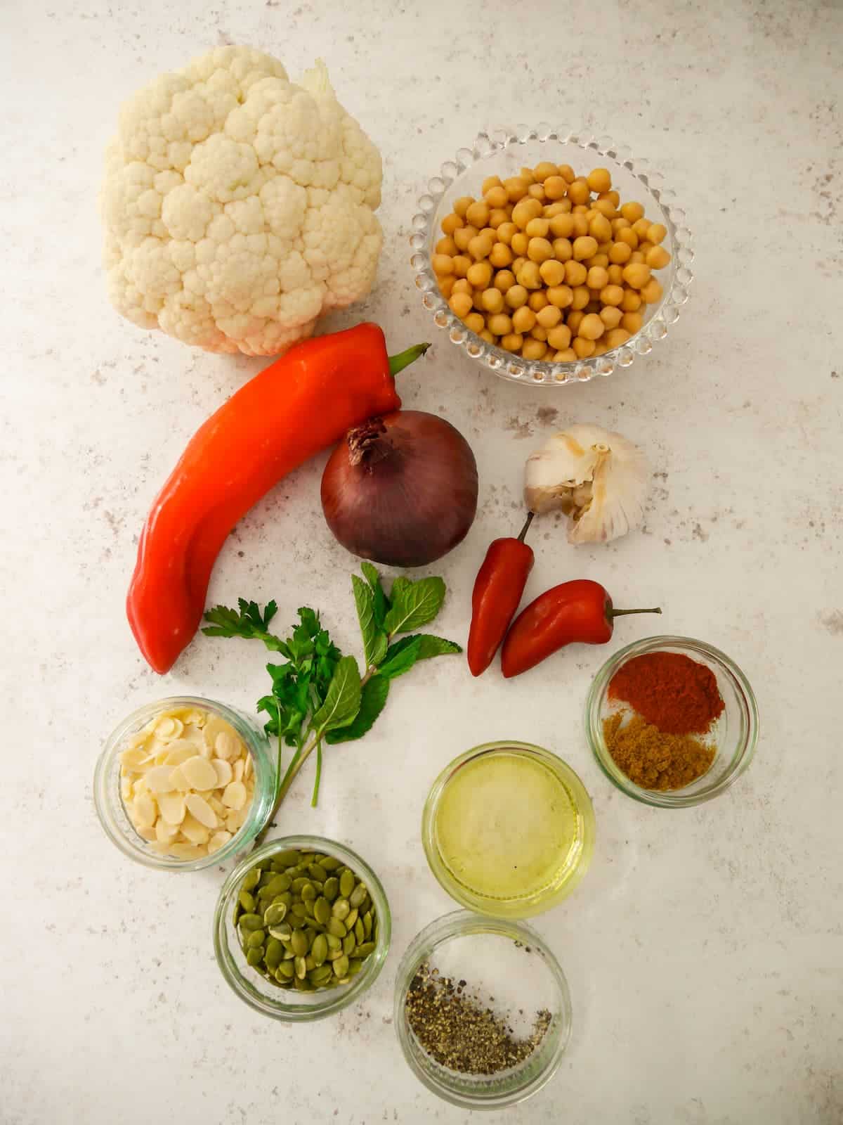 Individual recipe ingredients for making a bowl of roasted cauliflower and chickpeas.