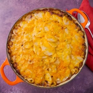 A cast iron skillet filled with chicken and bacon bake in a cider sauce.