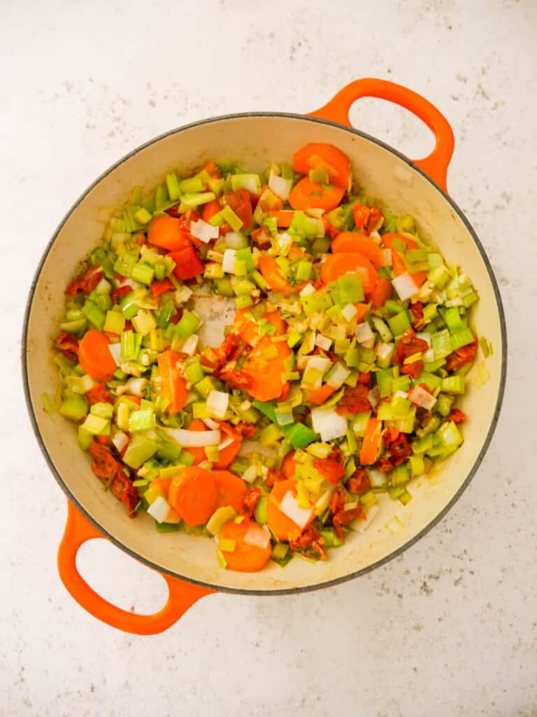 A cast iron skillet filled with sauteed leeks, carrots, garlic and sun blush tomatoes.