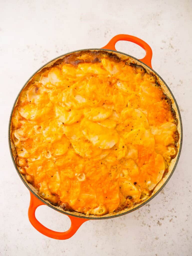 A cast iron skillet with cooked chicken and bacon bake.