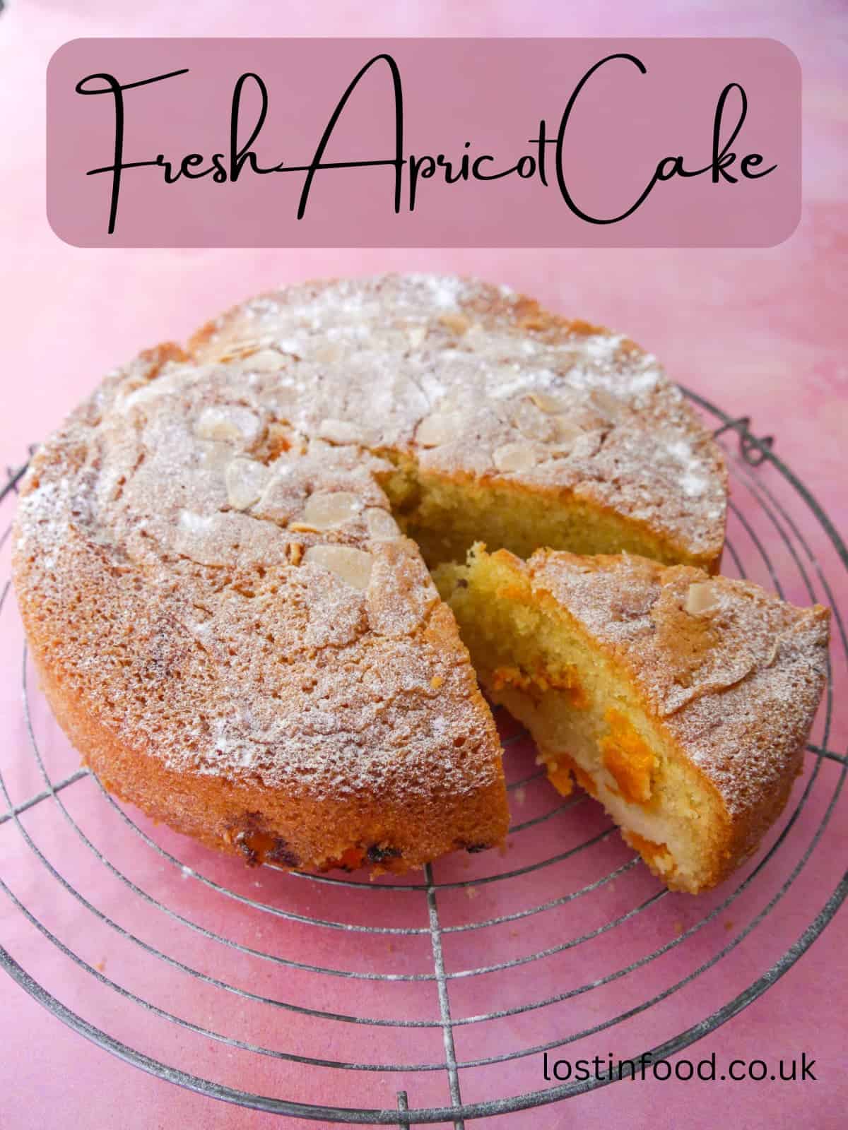 Pinnable image with recipe title and a photo of a fresh apricot cake set on a wire cooling rack with a slice cut from the cake.