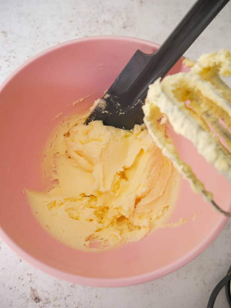 A pink bowl with butter and sugar creamed together.