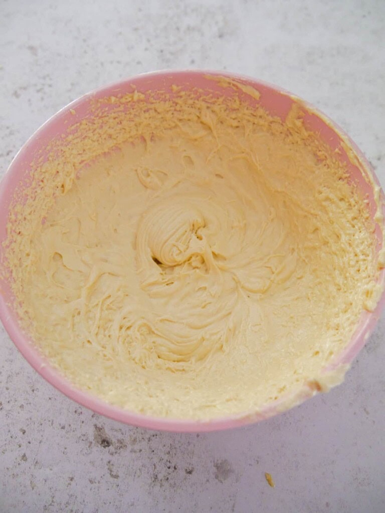 A pink bowl with creamed vanilla sponge cake mixture.
