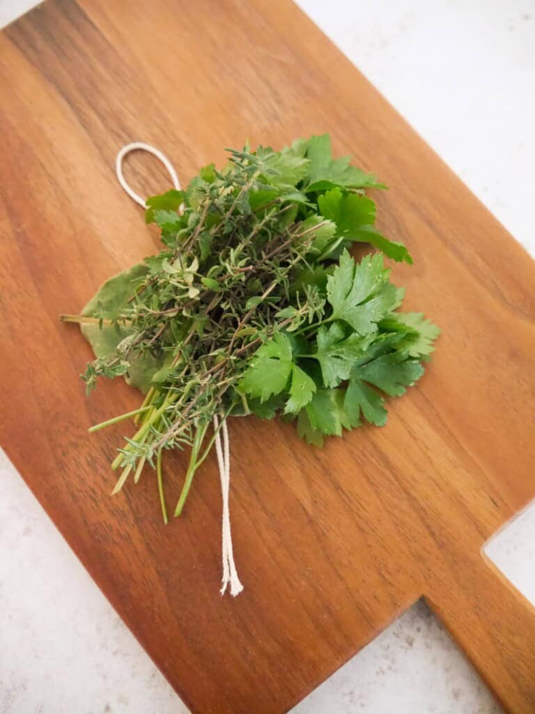 Fresh bay leaf, thyme a parsley, set out to wrap into a bouquet garni.