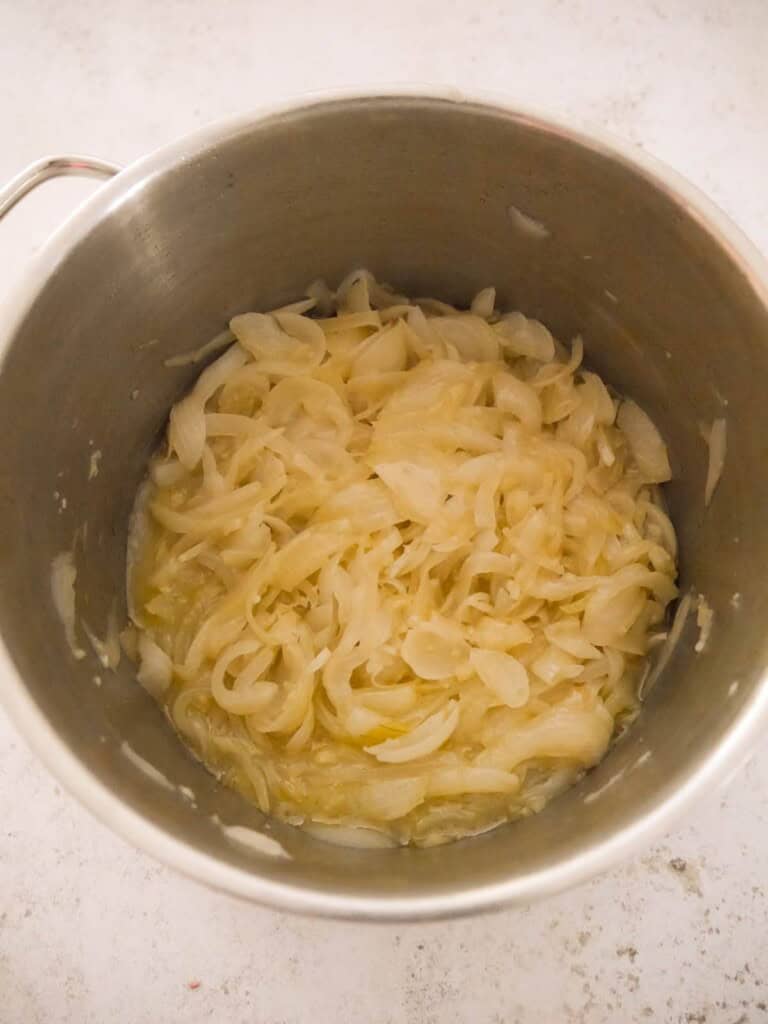 A large saucepan of sauteed onions and garlic with reduced white wine.