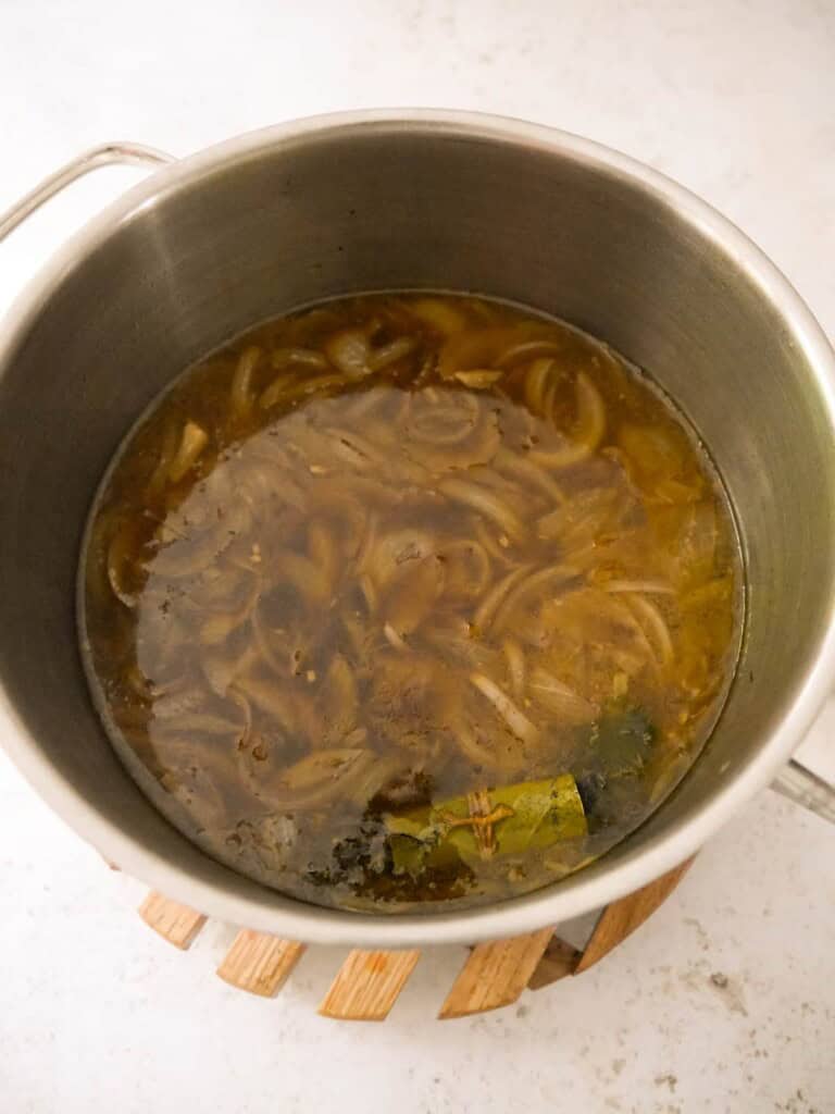 A large saucepan of cooked French onion soup.