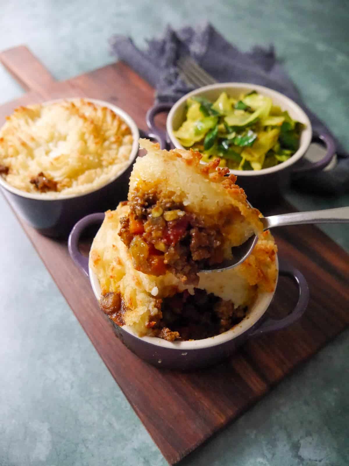 2 small dishes of masala spiced cottage pie, served with a bowl of mustard spiced cabbage set alongside.