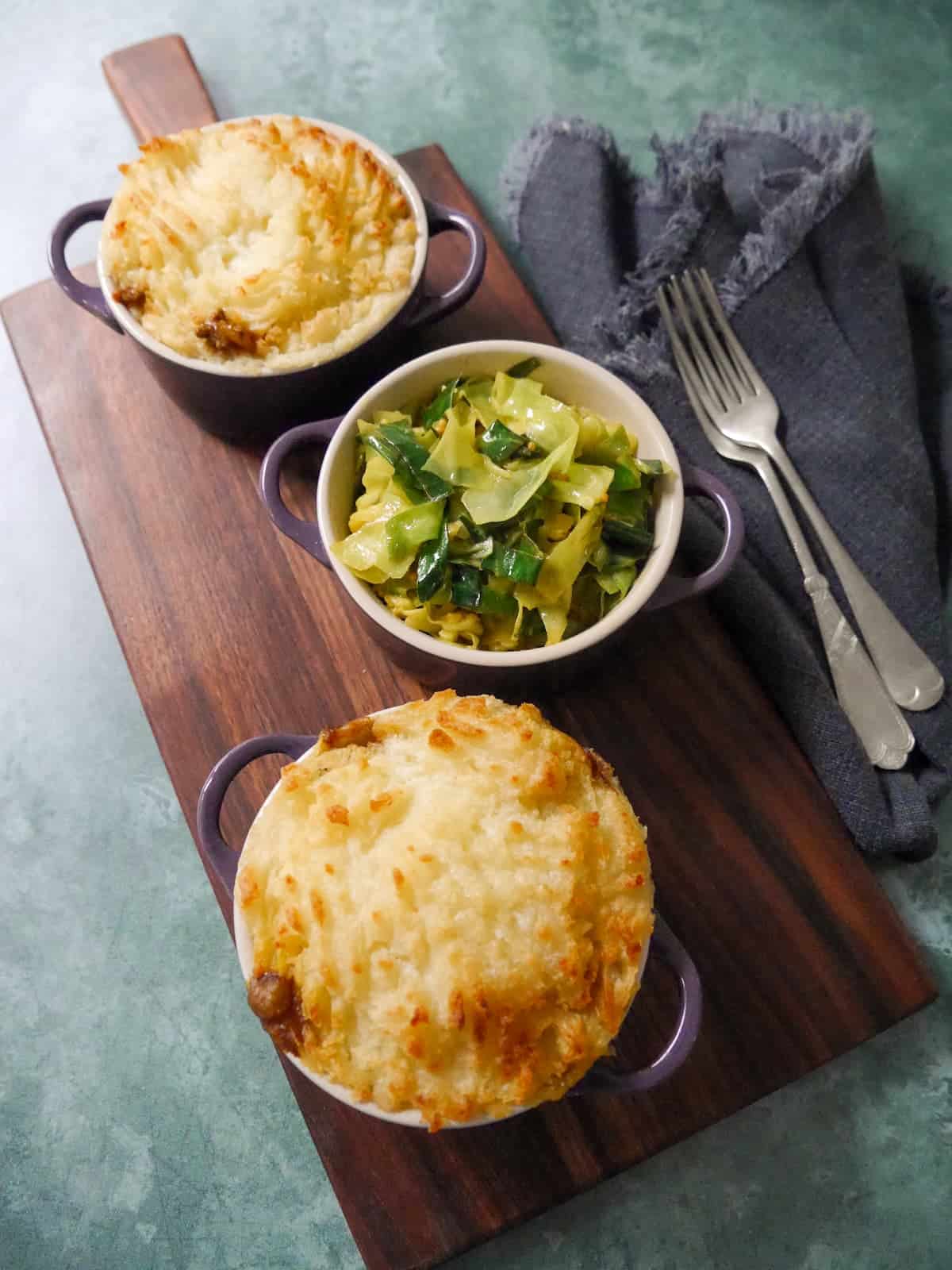 2 small dishes of masala spiced cottage pie, served with a bowl of mustard spiced cabbage set alongside.