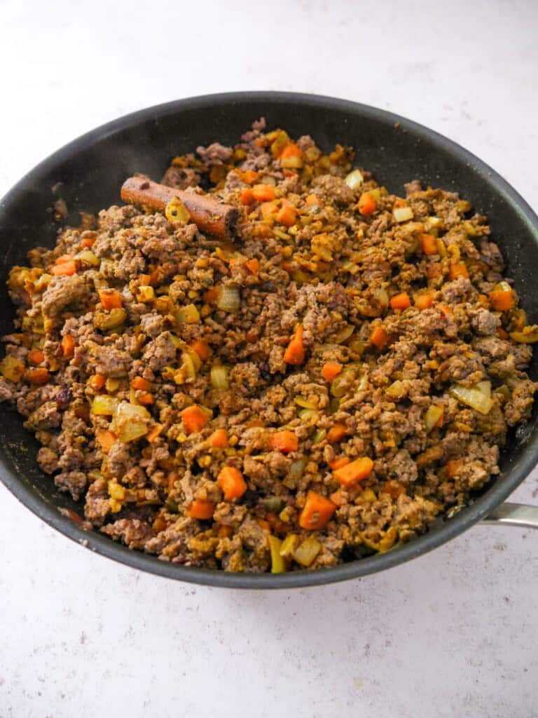 A large frying pan of sauteed and spiced minced beef and vegetables.